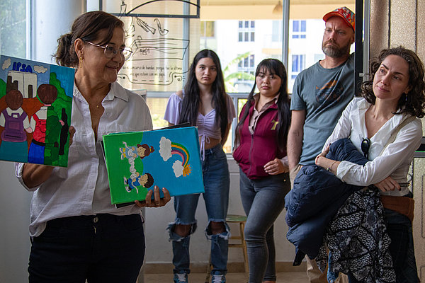 Lehrerin Martha Andrade (links) präsentiert das "Museum der Erinnerung" in der Schule von Samaniego. Zu sehen sind Gemälde ihrer Schüler, die auf Recherchen und Gesprächen mit Überlebenden des bewaffneten Konflikts basieren - ein beeindruckendes Beispiel für lebendige Erinnerungsarbeit und Friedenserziehung.